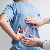 Chiropractor examines a patient's back to figure out where the pain is coming from